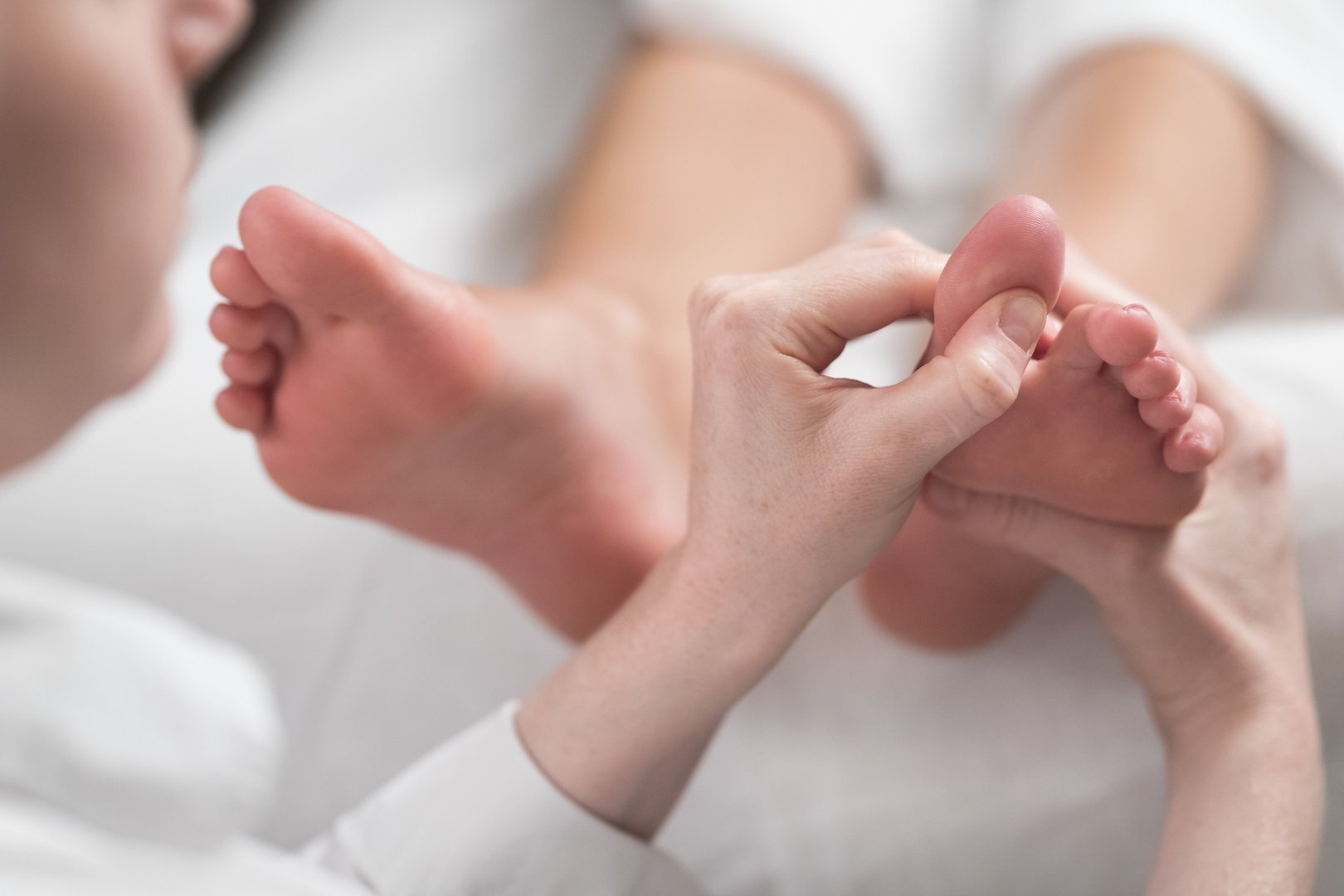 Professional Female Masseur Giving Reflexology Massage to Woman Foot